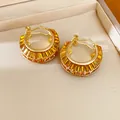 Close-up of luxurious golden hoop earrings featuring amber baguette crystals in a jewelry box - Brown