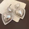 Detail view of vintage silver glossy heart drop earrings with a textured ridged border. - Silver