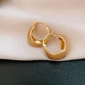 Macro view of 18K gold plated hoop earrings featuring a sophisticated brushed metal texture - Gold