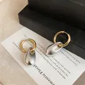 Detail shot of elegant two-tone hoop earrings with silver wrinkled teardrop pendants - Hoop - Gold - Silver