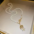 Detailansicht einer Perlenkette mit einem mit Strass besetzten Fischschwanz-Anhänger. - Halskette / Gold-Weiß