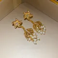Detail von Vintage-Ohrringen in Goldoptik mit Strasssteinen und Perlen in einer Box. - Ohrringe (Silber Ohrringpfosten) / Gold-Weiß