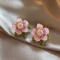 Close-up van elegante paarse bloem oorbellen met parels en kristallen op zijden stof. - 925 Zilveren Naald Echt Vergulde Stijl / Goud-Paars