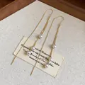 Detail view of elegant 18k gold plated tassel earrings with white pearls on linen - Ear Threader-Gold (HE31422)