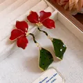 Close-up of exquisite red enamel flower earrings with green leaf pendants and gold accents. - Vintage Flower Dangle Style (HE33298) / Red and Green