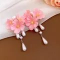 Close-up detail of pink cherry blossom flower earrings with elegant white pearl tassels. - Stud Earrings / Pink