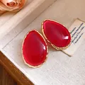 Primo piano di orecchini vintage in resina rossa con montatura dorata testurizzata. - Rosso Rosa (Ago d'argento)