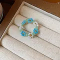 Détail d'une bague fleur artisanale en perles de verre avec pétales bleus et blancs - Bague / Bleu