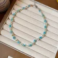 Détail en gros plan montrant les motifs de fleurs en perles bleues et blanches du collier. - Collier / Bleu