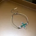 Detail view of a double-layered pearl and chain bracelet with a blue zircon cross. - Cross Bracelet (HB6048) / Silver-Green