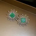 Macro view of luxury sunburst stud earrings featuring a brilliant square green stone - Radiant Sun Flower Stud Earrings (HE34013) / Silver-Green