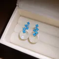 Close-up detail of silver stud earrings with blue stones and resin spheres in a box - Silver-Blue