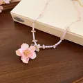 Dettaglio ravvicinato di un romantico ciondolo a rosa rosa su una collana di perline dorate - Rosa