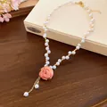 Dettaglio elegante di un ciondolo con rosa stabilizzata su una delicata collana di perle - Bianco-Rosa