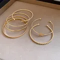 Macro view of a 6-piece gold-toned bracelet set featuring a star charm and twisted textures - 6-Piece Set / Gold