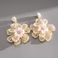 Detailed shot of raffia hand-woven floral earrings with delicate fabric flower center - White-Pink