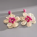 Detailed macro shot of handmade woven raffia flower earrings in cream and magenta tones - Rose Red