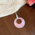 Primo piano di una collana con pendente in acrilico rosa e cordino in pelle crema minimal. - Ciondolo rotondo / Rosa