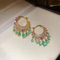 Detailed view of gold hoop earrings with purple and green zircon teardrop pendants. - Hoop Style / Gold-Purple-Green