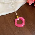 Primo piano di una collana con pendente in acrilico rosa su una superficie in legno - Pendaglio Quadrato / Rosa