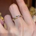 Detailansicht eines zierlichen goldenen Ährenrings mit bunten Edelsteinen am Finger - Gold Mehrfarbig