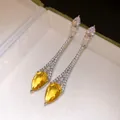 Gros plan détaillé de boucles d'oreilles en argent plaqué or 18k avec zircon jaune goutte d'eau - Pierre précieuse jaune / Argent