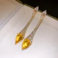 Gros plan de boucles d'oreilles pendantes plaquées or 18k avec zircons jaunes en goutte. - Pierre précieuse jaune / Or