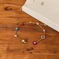 Detail view of a vintage gold charm bracelet with enamel flowers and ladybugs - Gold-Multicolor