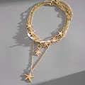 Detailed macro view of a layered gold necklace featuring starfish, turtle charms and pearls - Gold