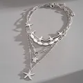 Close-up detail of a multi-layer silver necklace featuring starfish and sea turtle charms - Silver