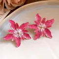 Detailed macro view of elegant pink and white enamel flower stud earrings with gold edges - Pink