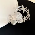 Close-up detail of silver starfish and seashell metal armlet bracelet jewelry design - Silver