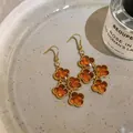 Macro detail of amber flower pendants and gold plated hooks with zircon accents - Gold Brown