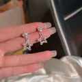 Close-up of silver-tone star dangle earrings with sparkling cubic zirconia inlay - Star Wrinkled Pendant Style / Silver