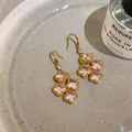 Detail of retro zircon flower tassel earrings on a ceramic plate with a perfume bottle. - Gold-Pink