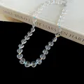 Detail of clear heart-shaped beaded necklace with colorful spacers on black background. - Transparent-Multicolor