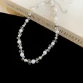 Close-up view of French style pearl necklace with silver accents and transparent flower beads - Silver-White