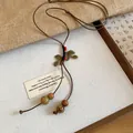 Detail of a vintage ethnic style necklace featuring bronze leaf charms and rustic beads - Coffee And Gold Leaf Style