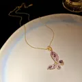 Detailed macro view of gold butterfly pendant inlaid with purple and white zircon. - Gold-Purple