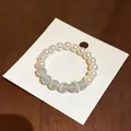 Elegante braccialetto con perle bianche e pietre occhio di gatto su carta bianca. - Stile 1 (HB5488)