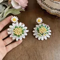 Primer plano de pendientes de margarita de cuentas hechos a mano con pétalos blancos y centro - Blanco-Verde