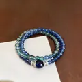 Detailed macro shot of vintage blue beaded bracelet set with silver floral accents. - Blue