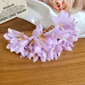 Vue détaillée de l'épingle à cheveux fleur en tissu rose avec perles d'eau sur bois. - Violet