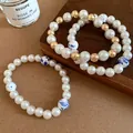Detailed macro view of vintage ceramic and pearl beaded bracelets with blue patterns. - Bracelet Set (3-Piece Set) / Gold-White-Blue