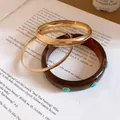 Detailed view of vintage resin bangle set with turquoise studs and gold circular rings - Three-Piece Set / Gold Brown