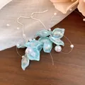 Close-up detail of sweet zircon petal and pearl tassel earrings on a rustic wooden surface. - Earring Hooks / Blue