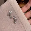 Dettaglio macro di eleganti orecchini a lobo con perle e zirconi su maglia rosa cipria - Stile Geometrico Perla Zirconia / Argento Con Rosa (Perno Argento)