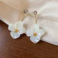 Close-up of resin flower earrings with rhinestone studs and gold plated stems - White