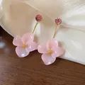 Close-up detail of pink resin flower earrings with gold-plated stems and rhinestones - Pink