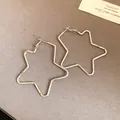 Close-up of oversized star-shaped silver-plated hoop earrings on a neutral background - Silver